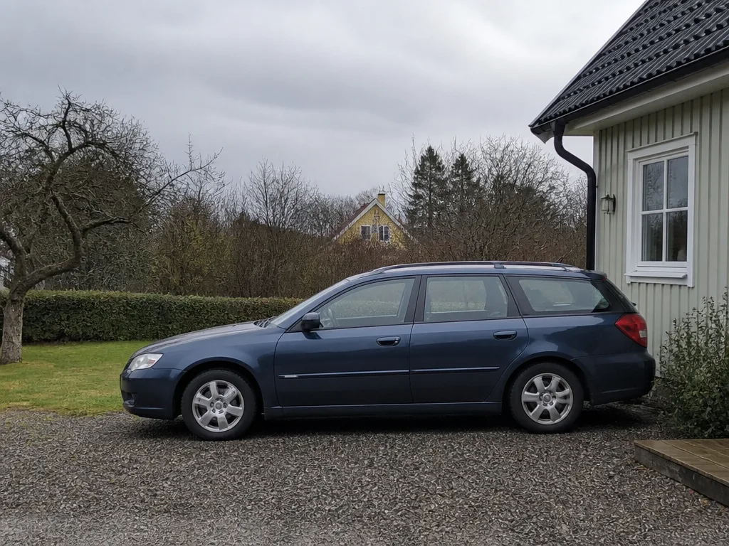 Familjebil parkerad på en uppfart utanför ett svenskt hus en molnig dag